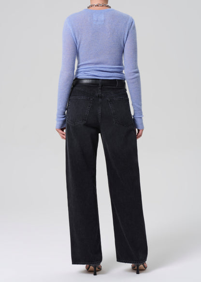 Person wearing a blue sweater and black pants on a white background