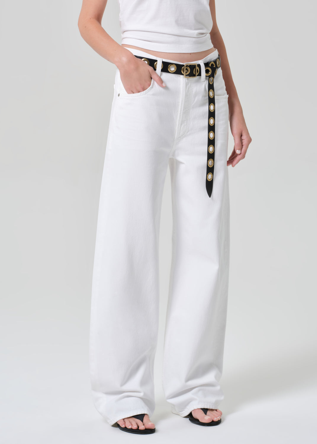 White pants with a decorative belt worn by a person on a white background