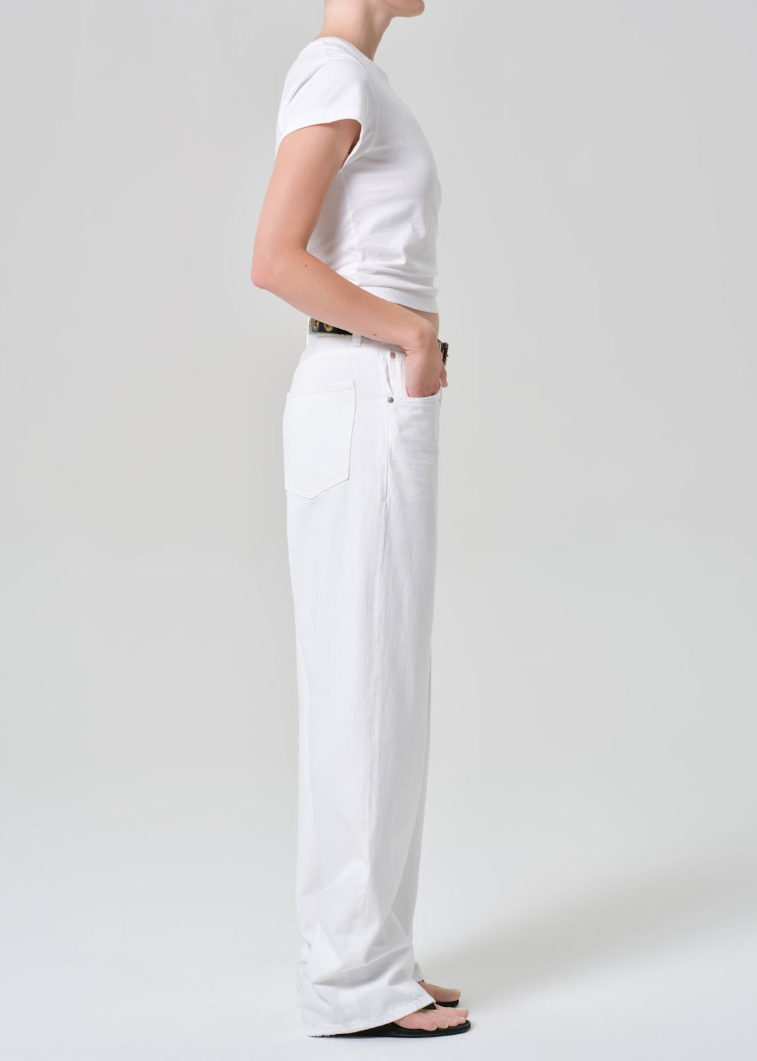 Person wearing a white t-shirt and pants on a plain background