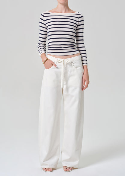 Person wearing a navy and white striped long-sleeve top and white wide-leg pants on a plain background