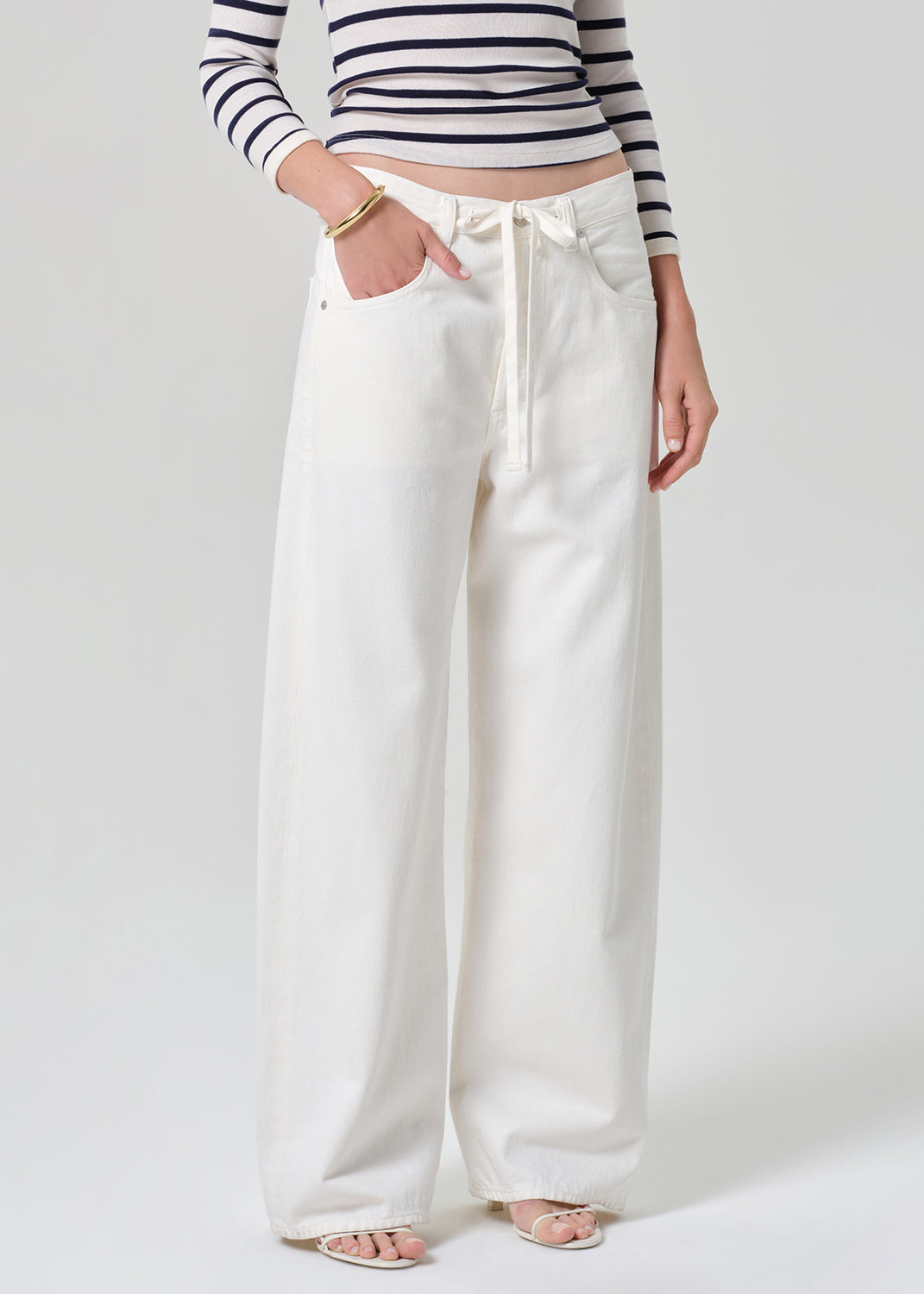 Person wearing a navy and white striped long-sleeve top and white wide-leg pants on a plain background