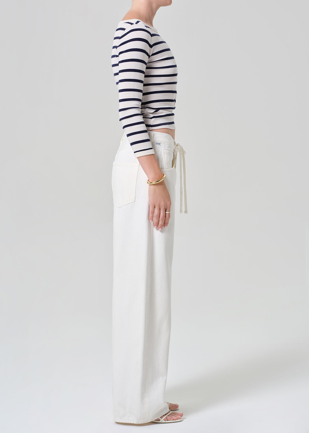 Person wearing a navy and white striped long-sleeve top and white wide-leg pants on a plain background