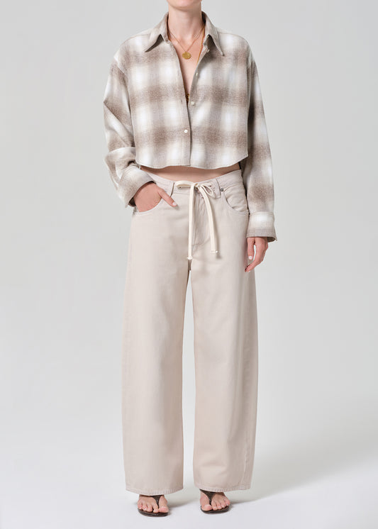 Person wearing a plaid shirt and beige pants on a grey background