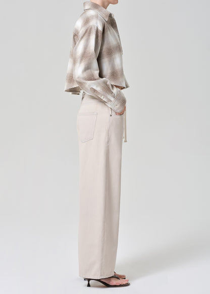 Person wearing a plaid shirt and beige pants on a grey background