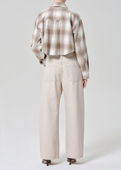 Person wearing a plaid shirt and beige pants on a grey background
