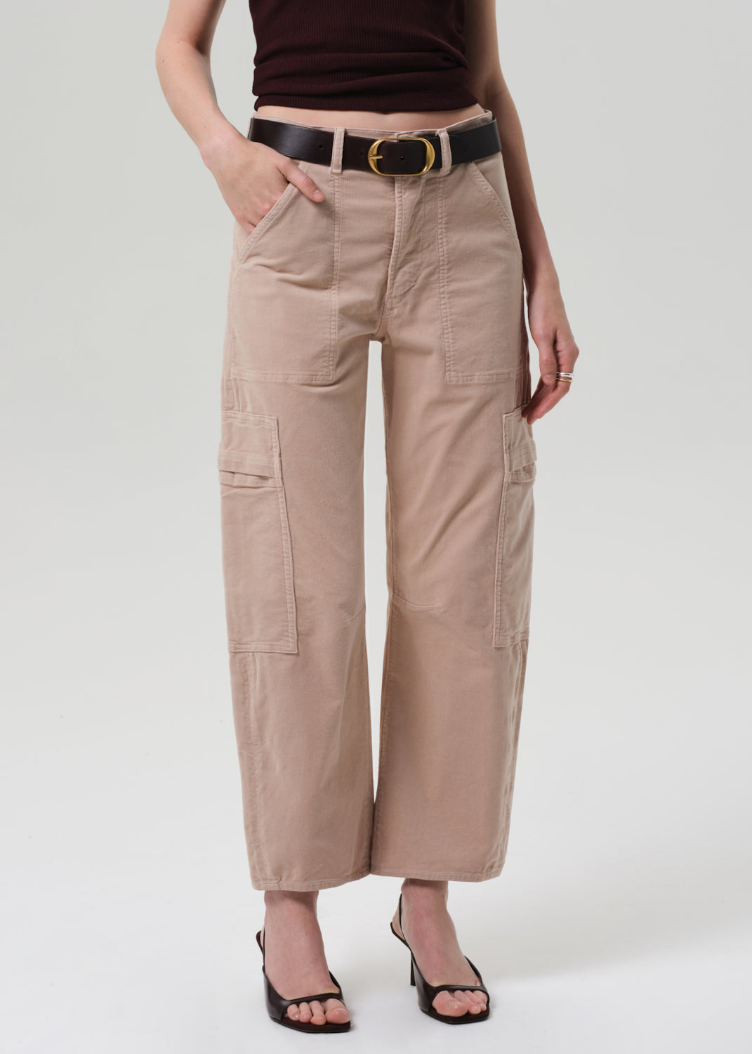 Person wearing beige cargo pants with a black belt on a white background