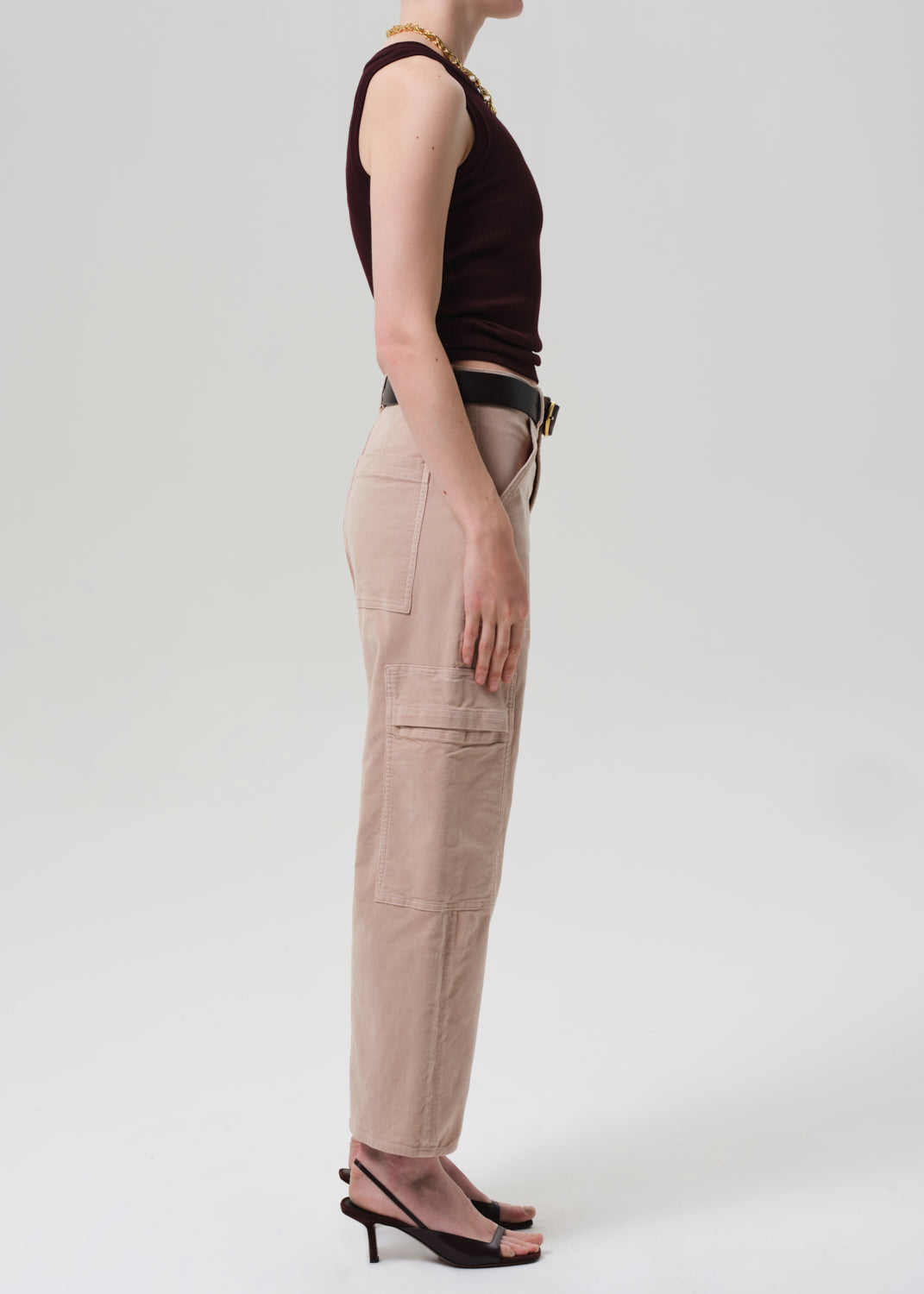 Person wearing a brown top and beige cargo pants on a white background