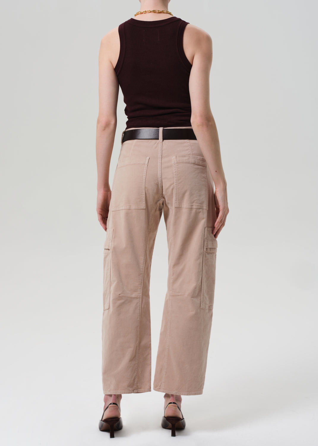 Person wearing a brown sleeveless top and beige cargo pants on a white background