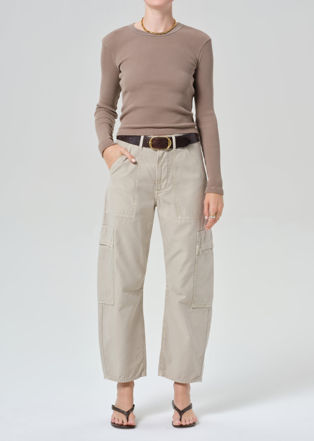 Person wearing a brown long-sleeve top and beige cargo pants on a plain background