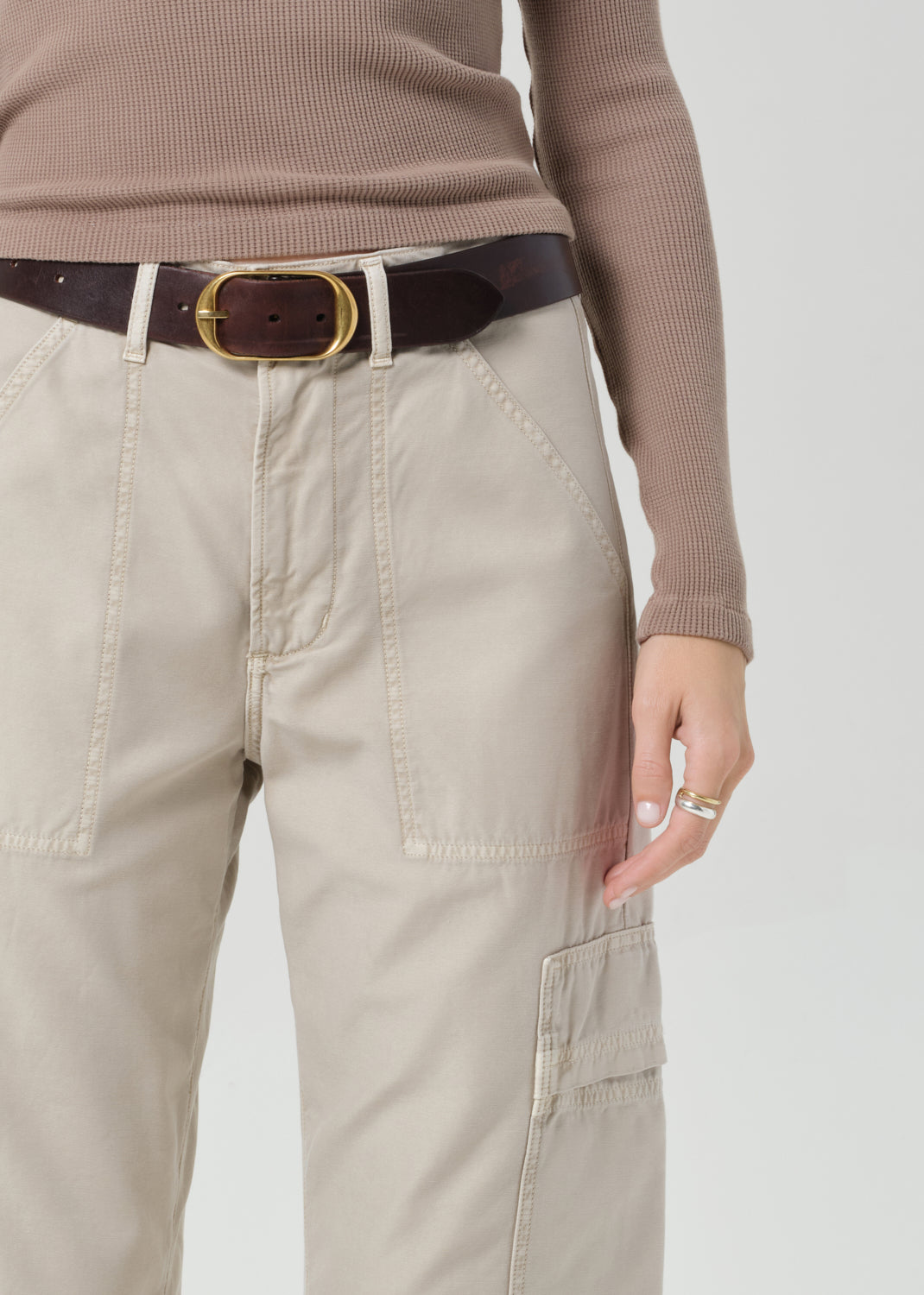 Person wearing a brown long-sleeve top and beige cargo pants on a plain background