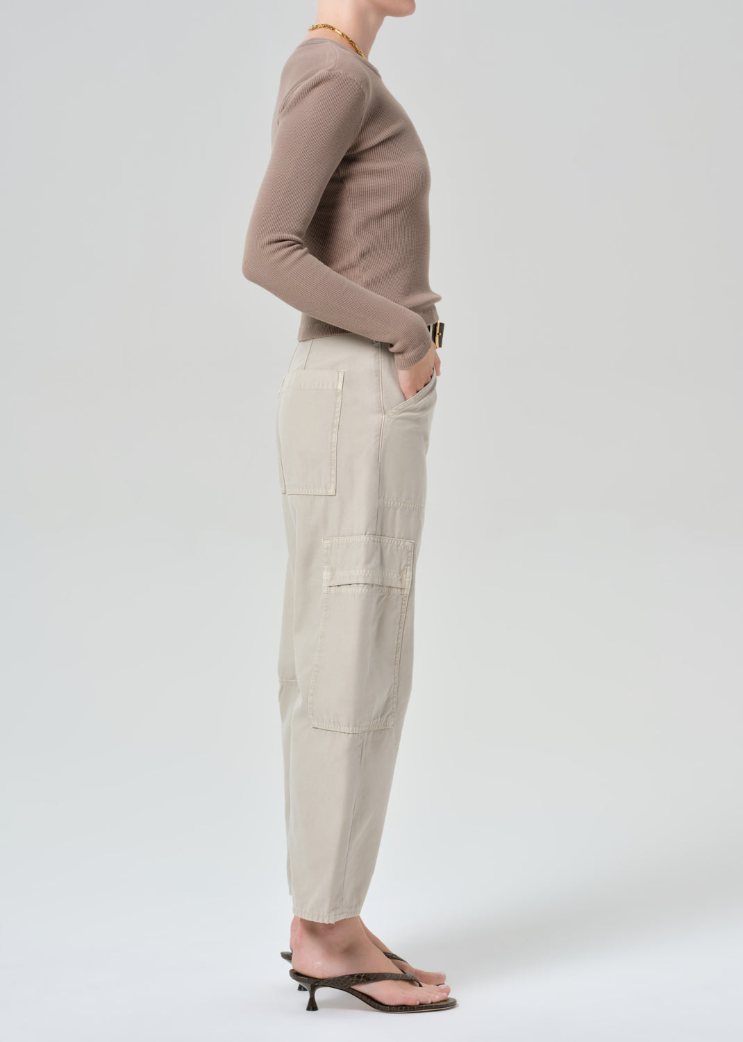 Person wearing a brown long-sleeve top and beige cargo pants on a plain background