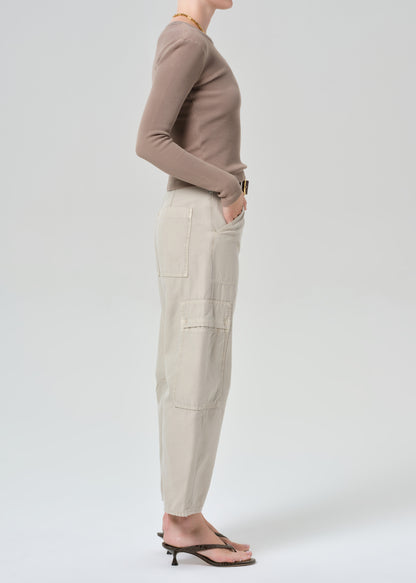 Person wearing a brown long-sleeve top and beige cargo pants on a plain background