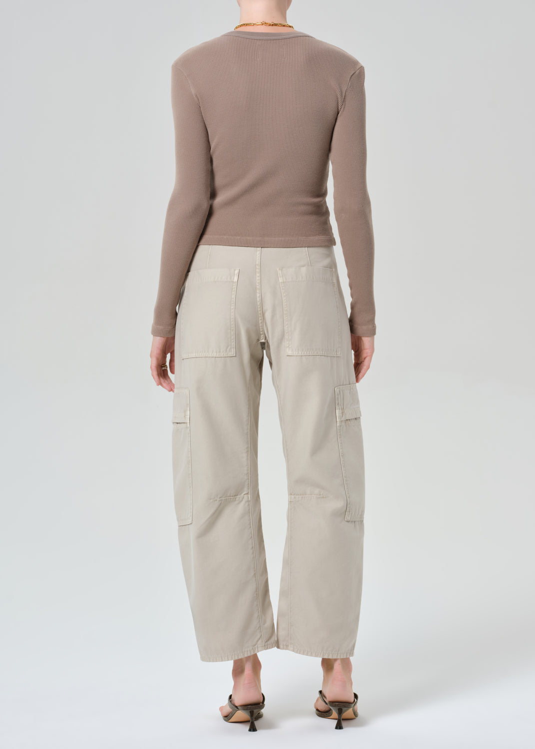Person wearing a brown long-sleeve top and beige cargo pants on a plain background