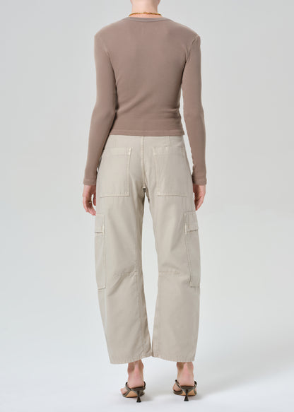 Person wearing a brown long-sleeve top and beige cargo pants on a plain background