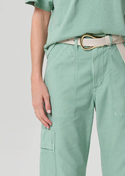Person wearing a green outfit with cargo pants on a grey background