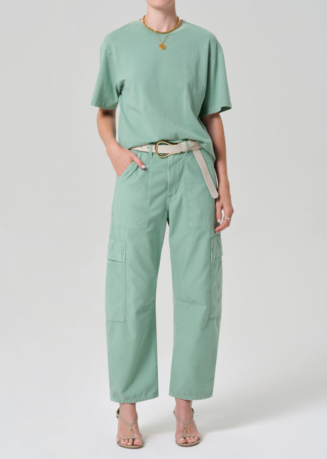 Person wearing a green outfit with cargo pants on a grey background
