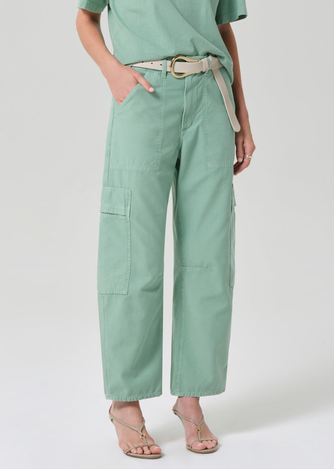 Person wearing a green outfit with cargo pants on a grey background