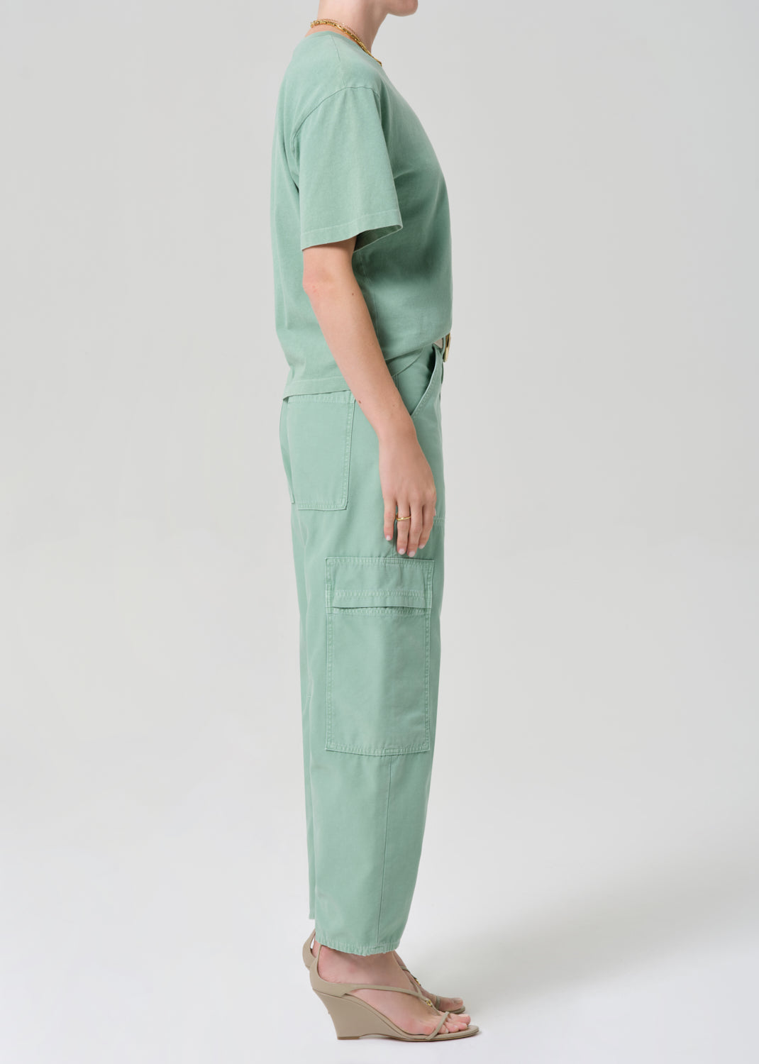 Person wearing a green outfit with cargo pants on a grey background
