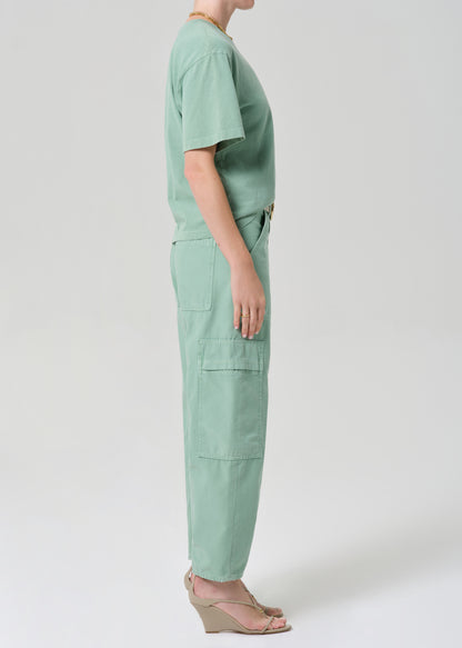 Person wearing a green outfit with cargo pants on a grey background