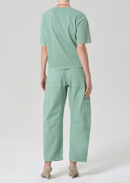 Person wearing a green outfit with cargo pants on a grey background