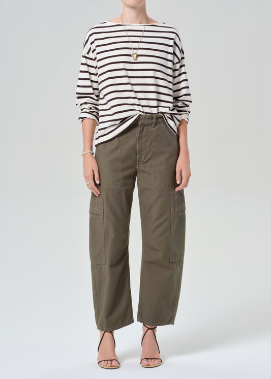 Person wearing a striped shirt and olive green cargo pants on a plain background