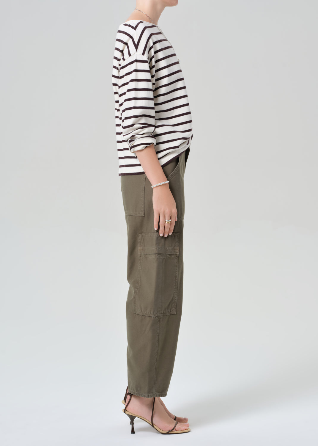 Person wearing a striped shirt and olive green cargo pants on a plain background