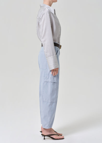 Person wearing a striped shirt and light blue cargo pants on a grey background