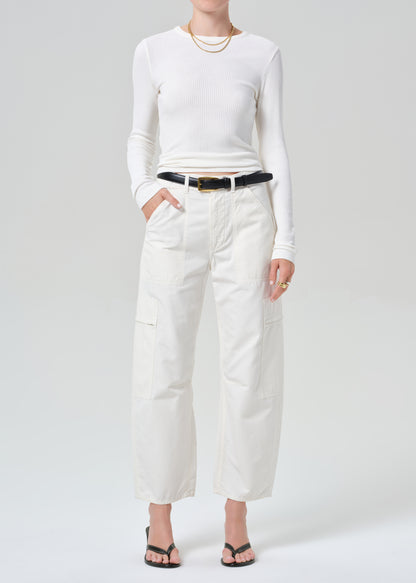 Person wearing a white long-sleeve top and white pants on a plain background