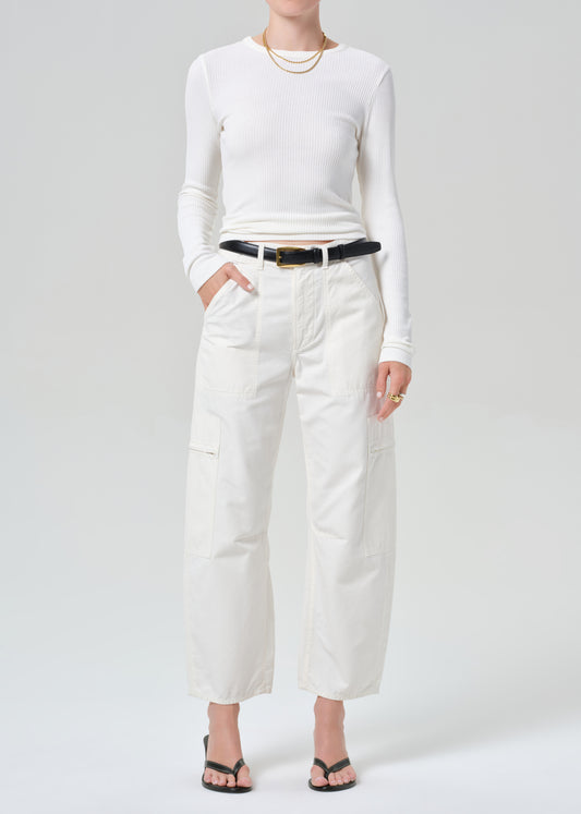 Person wearing a white long-sleeve top and white pants on a plain background