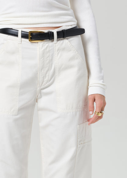 Person wearing a white long-sleeve top and light-colored pants with a black belt.