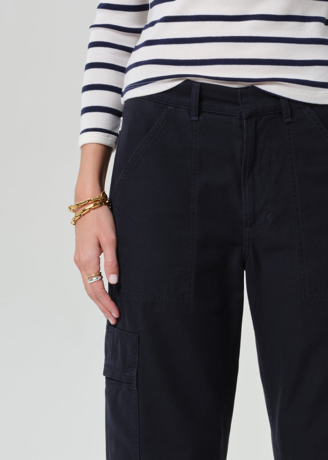 Person wearing a striped shirt with navy cargo pants on a light gray background