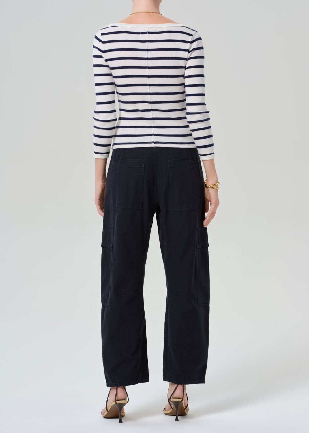 Person wearing a striped shirt with navy cargo pants on a light gray background