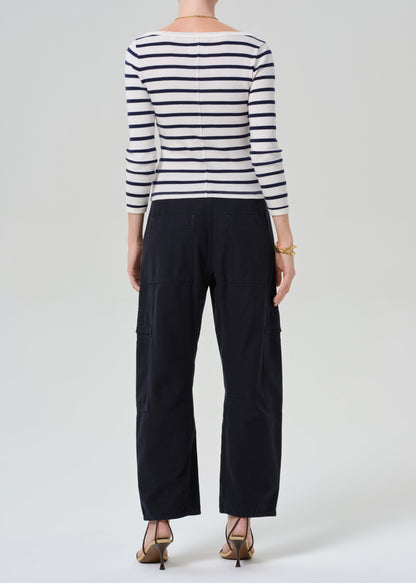 Person wearing a striped shirt with navy cargo pants on a light gray background