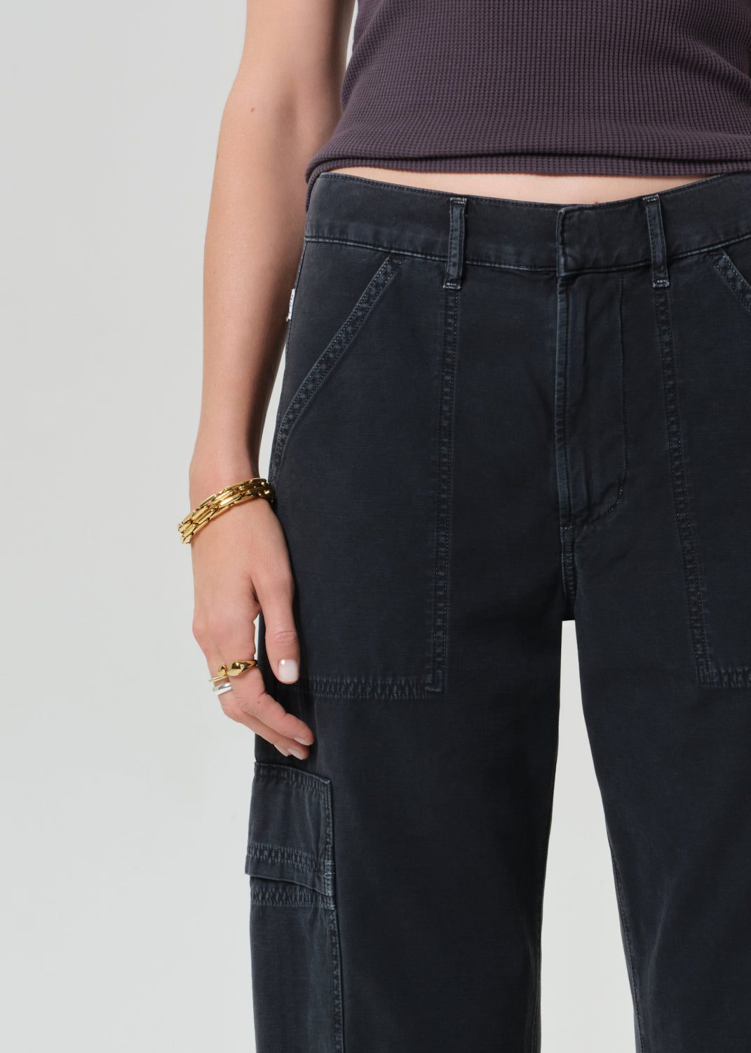 Person wearing a charcoal tank top and black cargo pants on a plain background