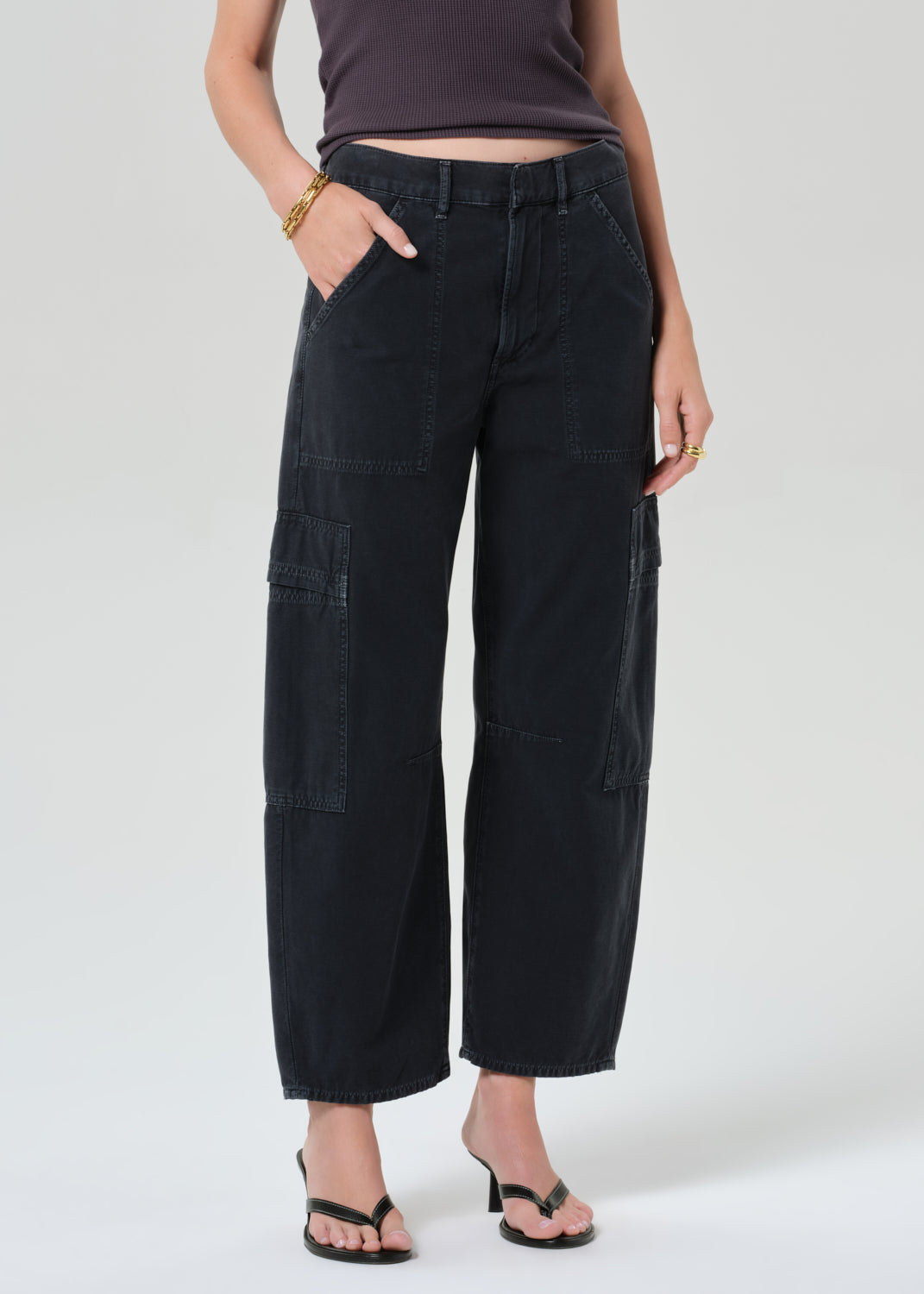 Person wearing a charcoal tank top and black cargo pants on a plain background