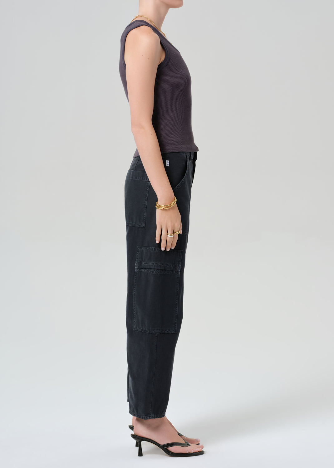 Person wearing a charcoal tank top and black cargo pants on a plain background