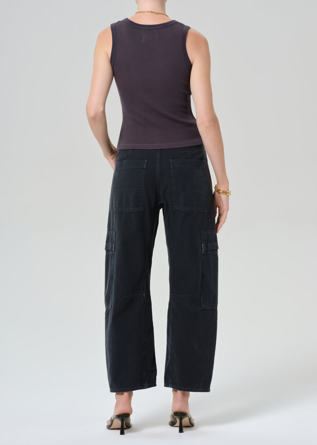 Person wearing a charcoal tank top and black cargo pants on a plain background