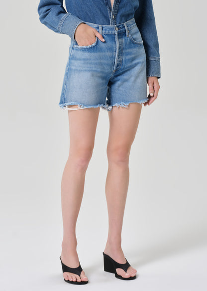 Person wearing a denim shirt and shorts on a grey background