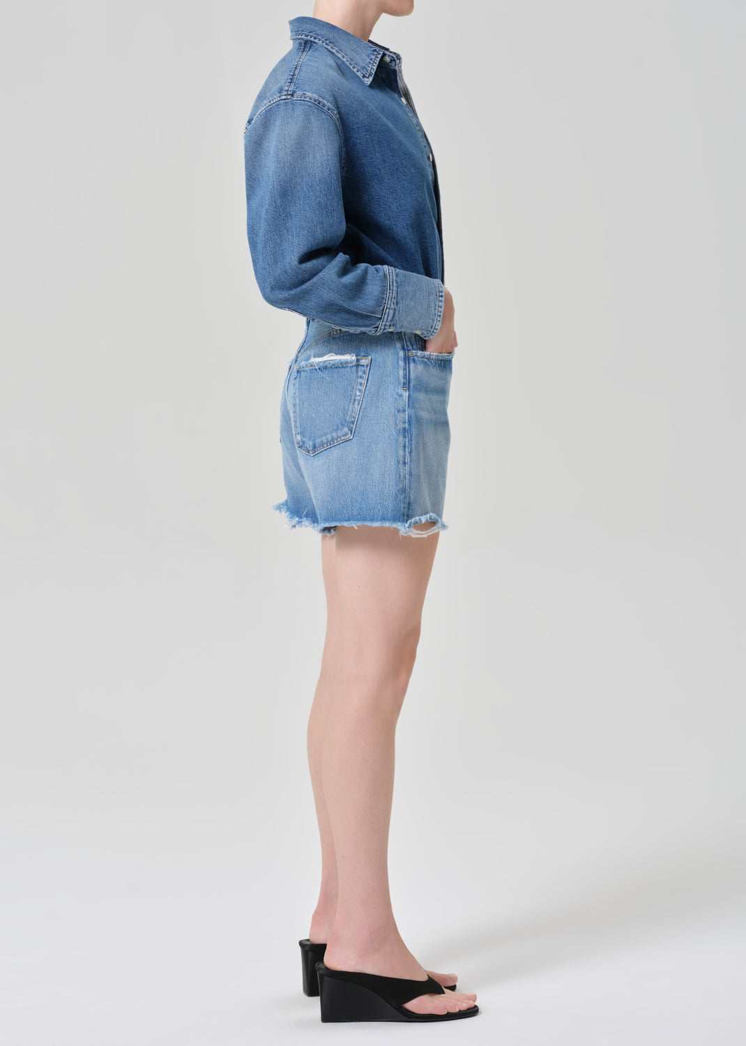 Person wearing a denim shirt and shorts on a grey background