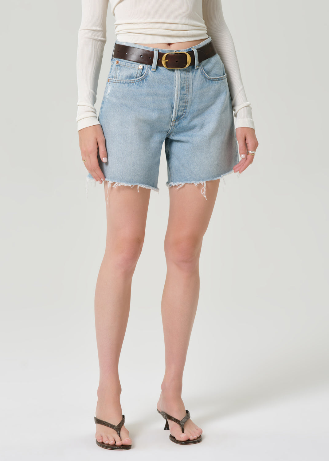 Person wearing light blue denim shorts on a grey background