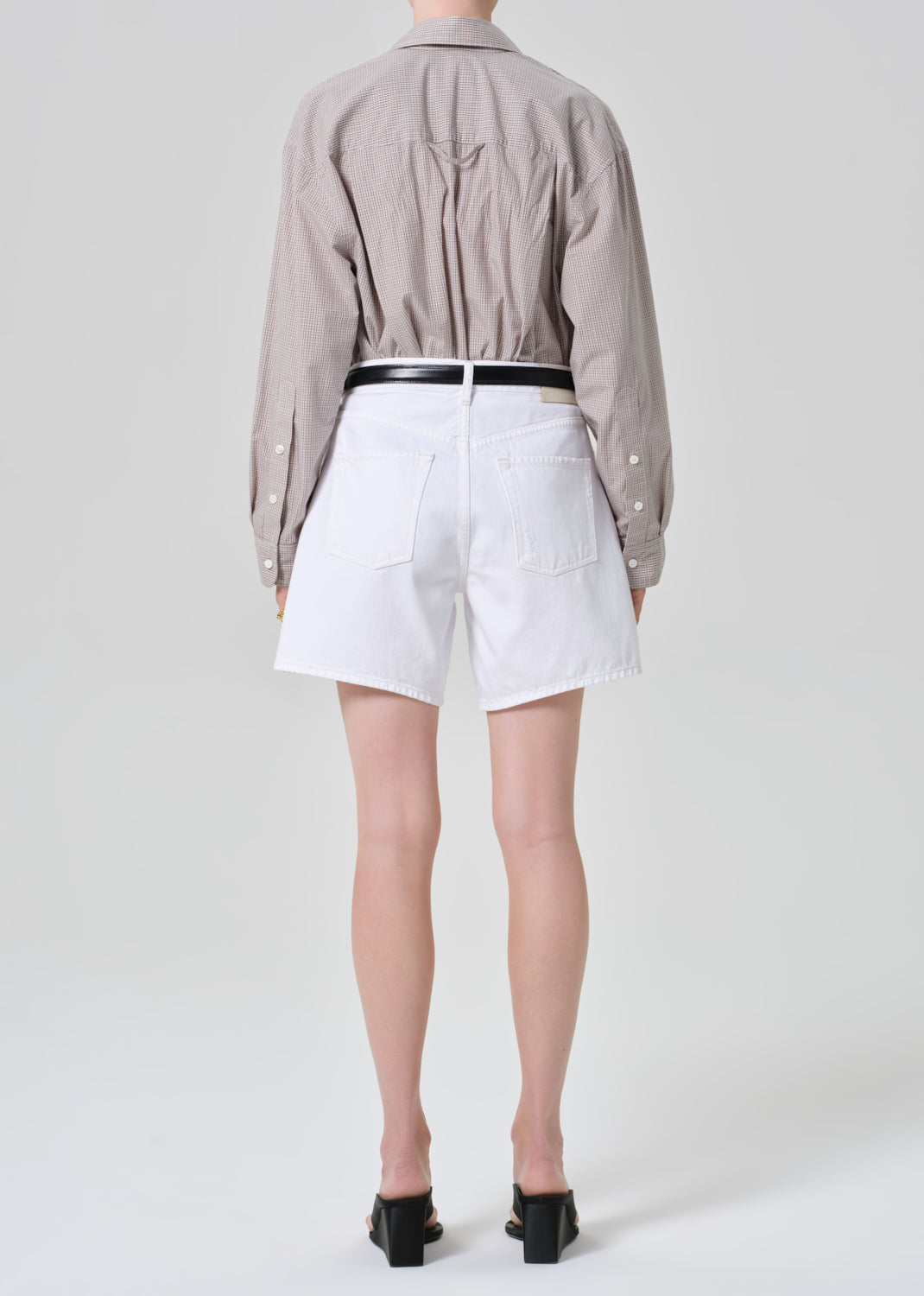 Person wearing a shirt and white shorts on a plain background