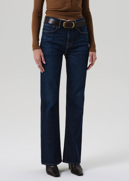 Person wearing dark blue jeans and a brown top on a white background