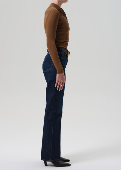 Person wearing a brown top and blue jeans on a white background