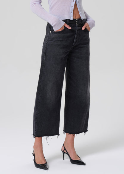 Person wearing black wide-leg jeans and black high-heeled shoes on a white background