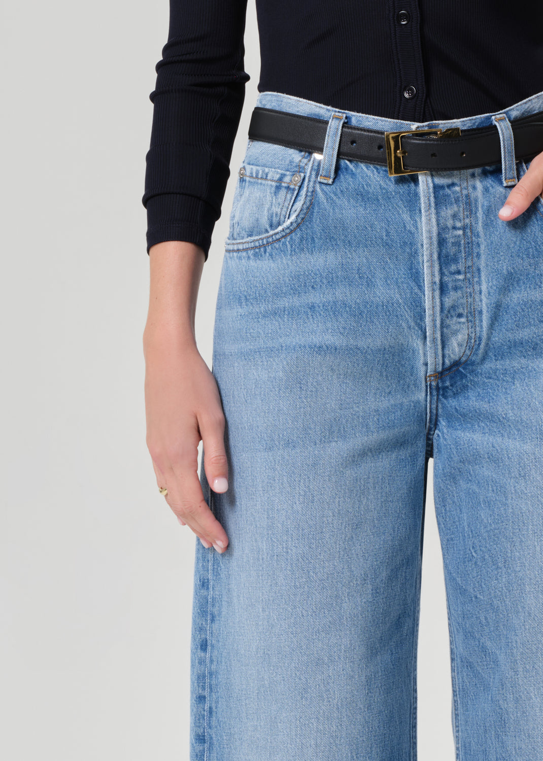 Person wearing a navy shirt and blue jeans on a grey background