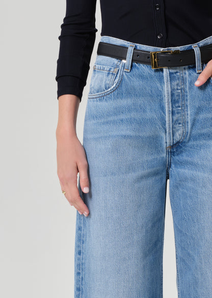 Person wearing a navy shirt and blue jeans on a grey background