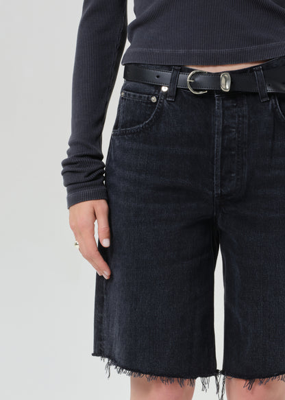 Person wearing a charcoal long-sleeve shirt and blank denim shorts on a grey background