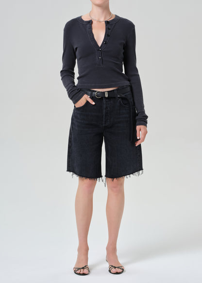 Person wearing a charcoal long-sleeve shirt and blank denim shorts on a grey background