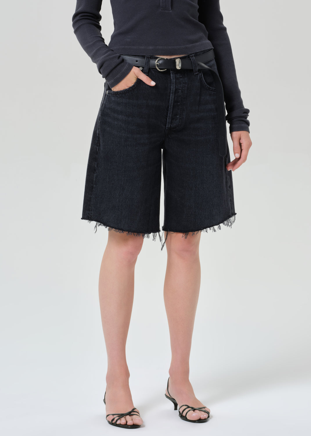 Person wearing a charcoal long-sleeve shirt and blank denim shorts on a grey background