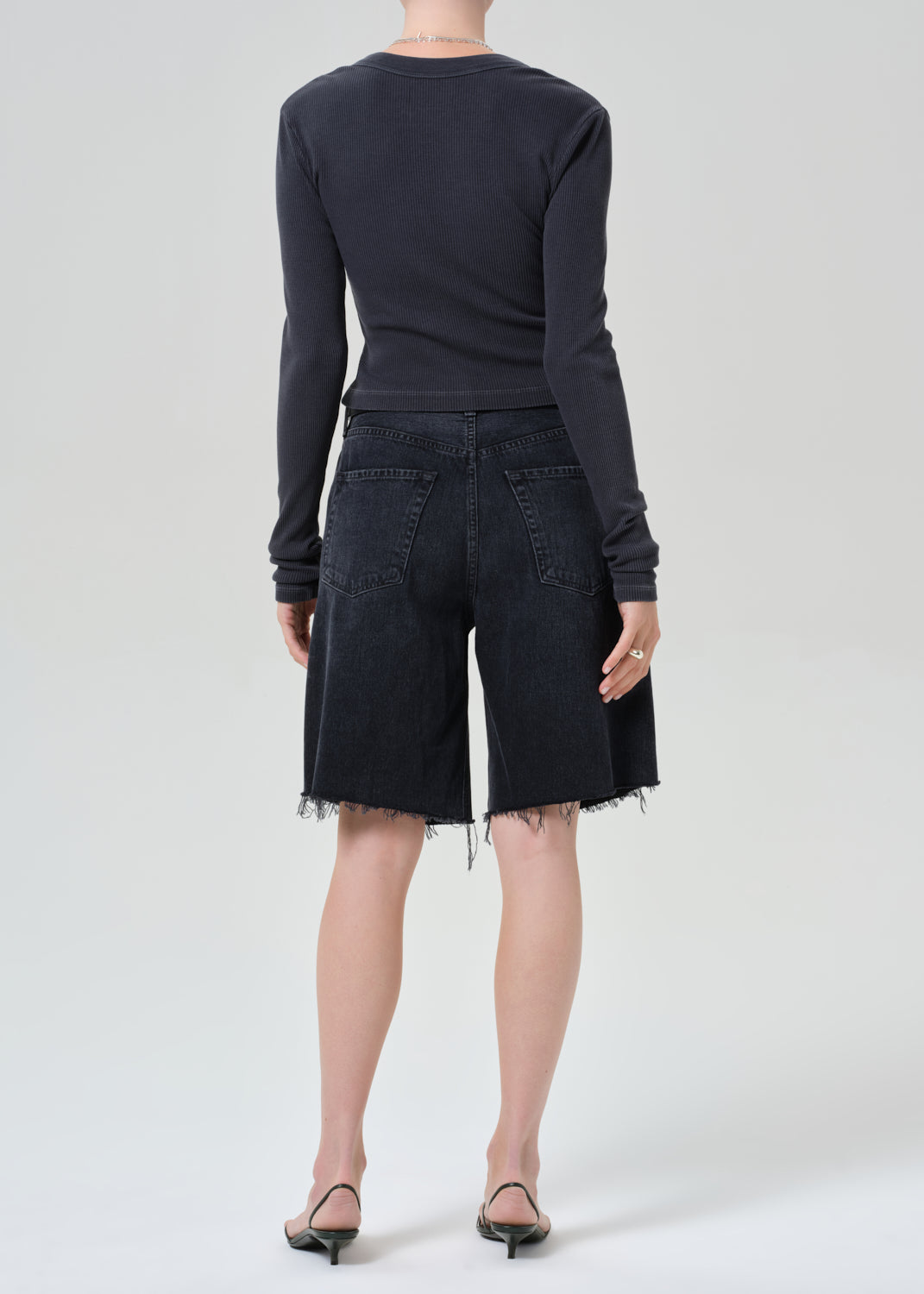 Person wearing a charcoal long-sleeve shirt and blank denim shorts on a grey background